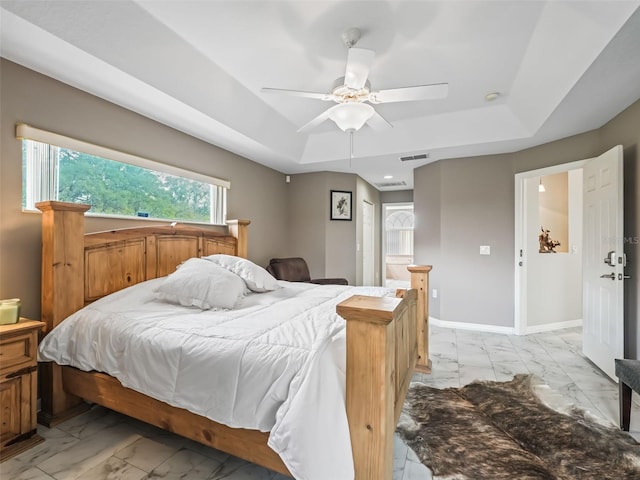 bedroom with marble finish floor, baseboards, visible vents, and a tray ceiling