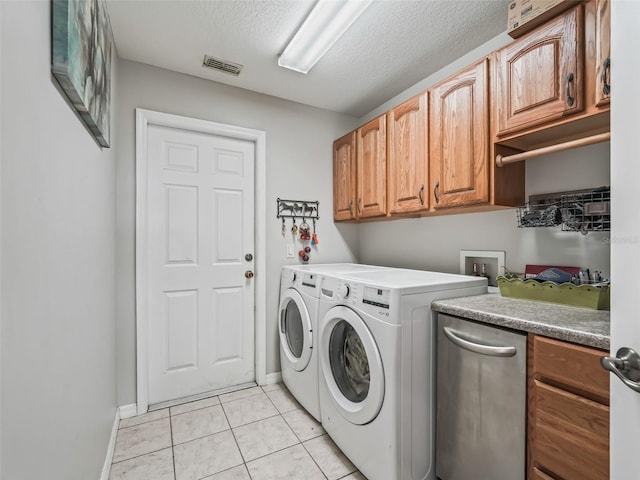 laundry area featuring cabinet space, visible vents, washer and clothes dryer, a textured ceiling, and light tile patterned flooring