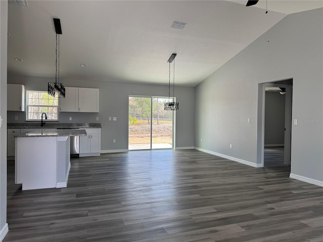 kitchen with a center island, open floor plan, white cabinetry, vaulted ceiling, and ceiling fan with notable chandelier