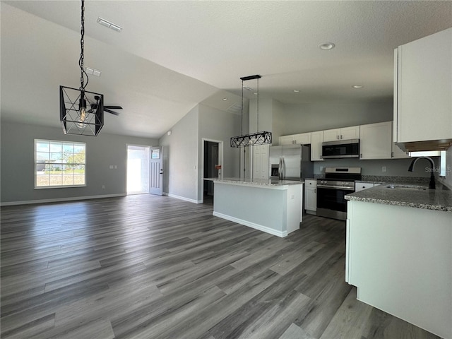 kitchen featuring pendant lighting, appliances with stainless steel finishes, open floor plan, white cabinets, and a sink