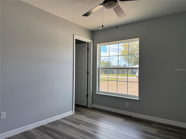 spare room with plenty of natural light, baseboards, wood finished floors, and a textured wall