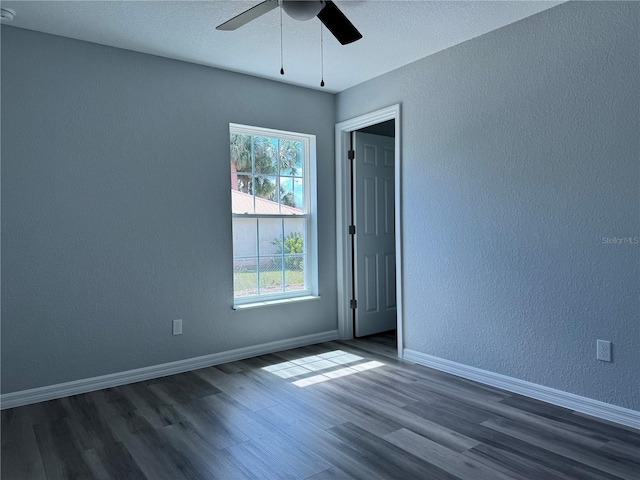 unfurnished room featuring a textured wall, wood finished floors, a ceiling fan, and baseboards