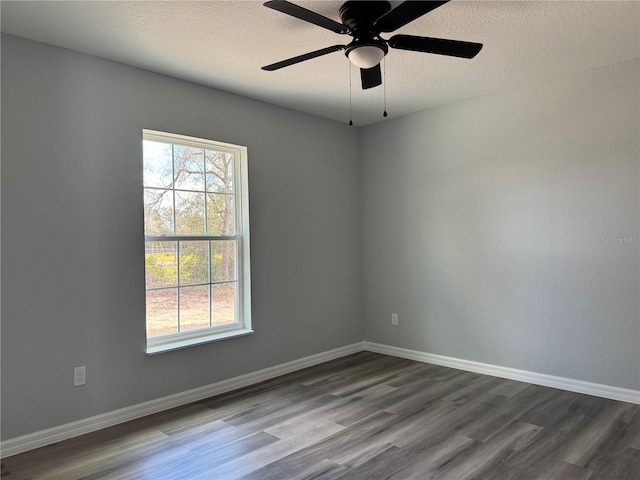 spare room with a textured ceiling, dark wood-style flooring, a ceiling fan, and baseboards