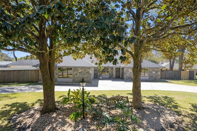 view of front of house featuring stone siding, fence, and a front lawn