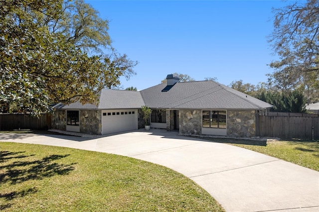 view of front facade with stone siding, an attached garage, fence, and a front yard