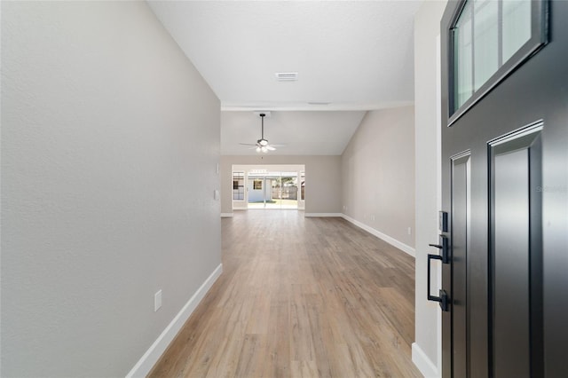 hall featuring lofted ceiling, light wood finished floors, visible vents, and baseboards