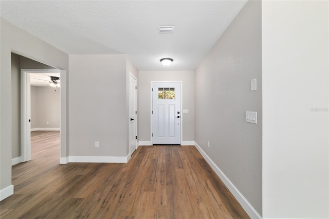 entryway with dark wood-style flooring, visible vents, a textured ceiling, and baseboards