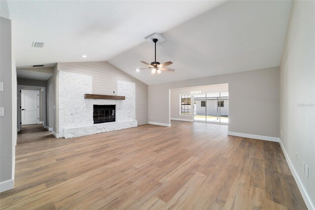 unfurnished living room with a fireplace, lofted ceiling, visible vents, ceiling fan, and light wood-type flooring