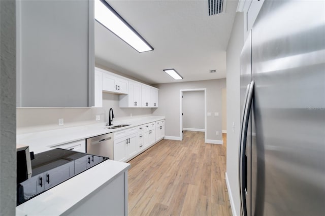 kitchen featuring stainless steel appliances, a sink, visible vents, and white cabinetry