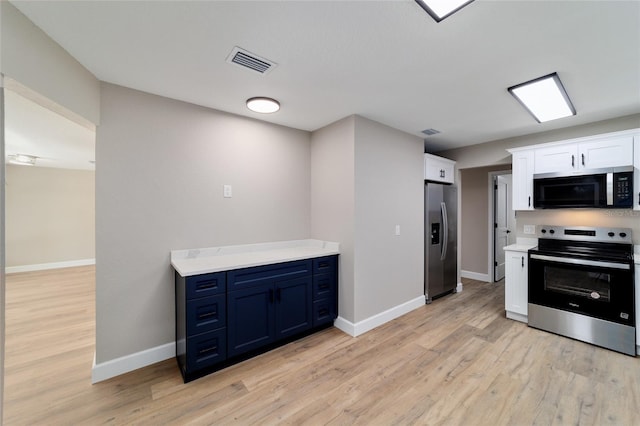 kitchen with light wood-style flooring, stainless steel appliances, visible vents, white cabinetry, and light countertops