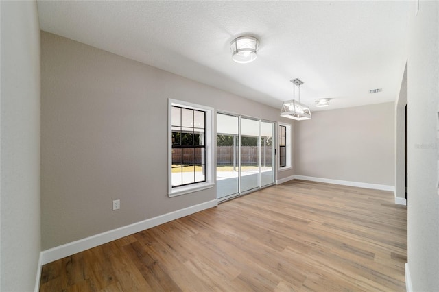 empty room with visible vents, light wood-style flooring, and baseboards