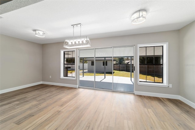 spare room with a textured ceiling, baseboards, and wood finished floors