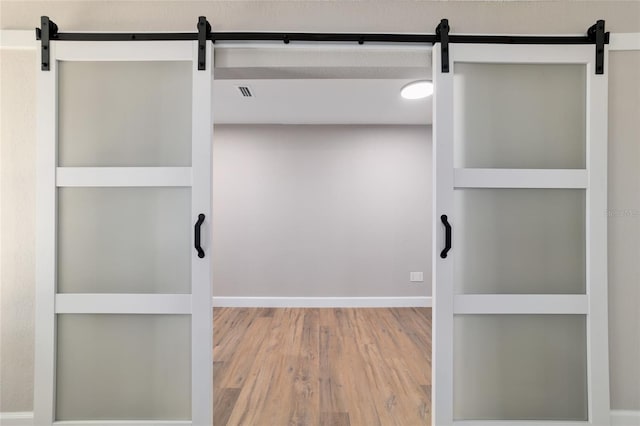 interior space featuring wood finished floors, visible vents, and a barn door