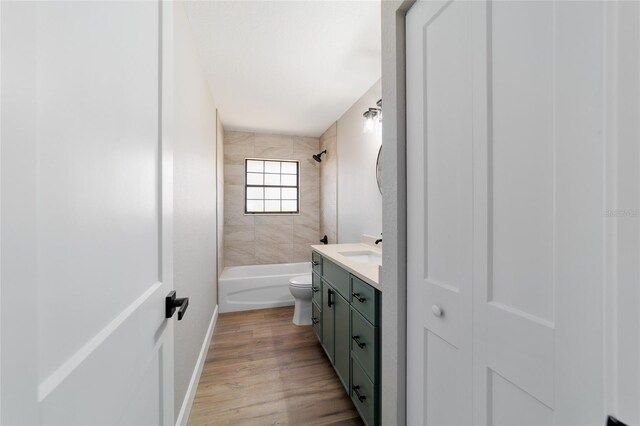 full bath with baseboards, bathing tub / shower combination, toilet, wood finished floors, and vanity