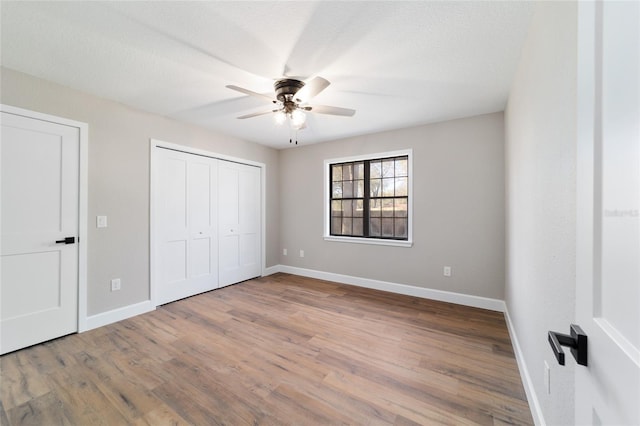 unfurnished bedroom with baseboards, ceiling fan, wood finished floors, a textured ceiling, and a closet