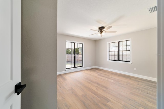 spare room featuring visible vents, ceiling fan, light wood-style flooring, and baseboards