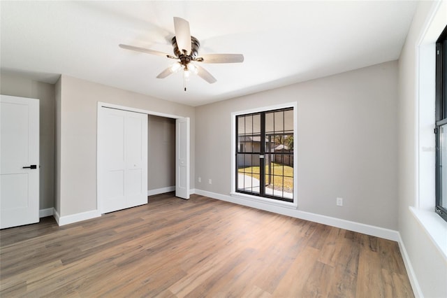 unfurnished bedroom with ceiling fan, a closet, wood finished floors, and baseboards