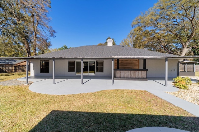 back of house with a patio, a lawn, fence, and stucco siding