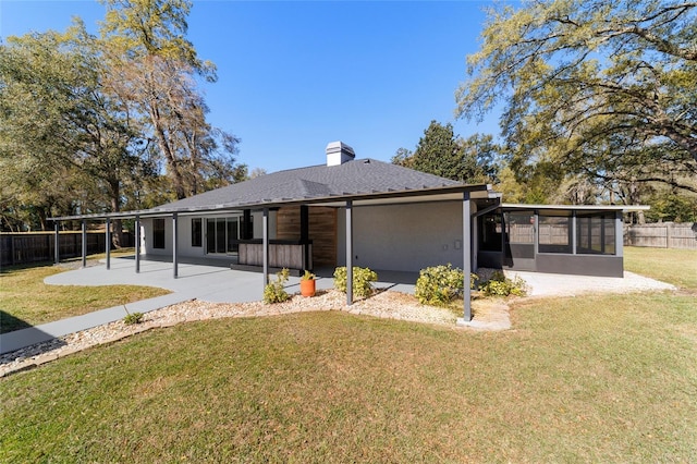 rear view of property with a patio, fence, a sunroom, a yard, and a chimney