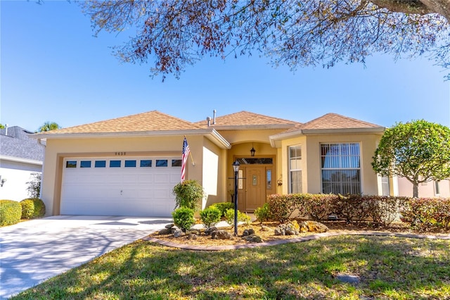 view of front facade with a garage, driveway, and stucco siding