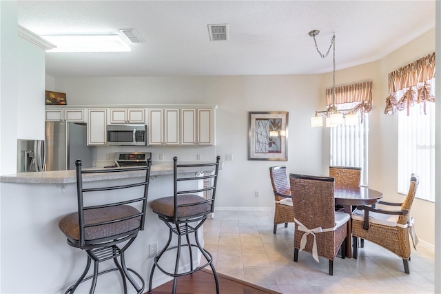 9458 SW 93rd Loop, Ocala, FL 34481 - kitchen with stainless steel appliances, a breakfast bar, light countertops, decorative light fixtures, and light tile patterned floors