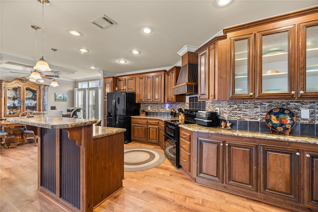 kitchen featuring visible vents, backsplash, a breakfast bar area, custom exhaust hood, and black appliances