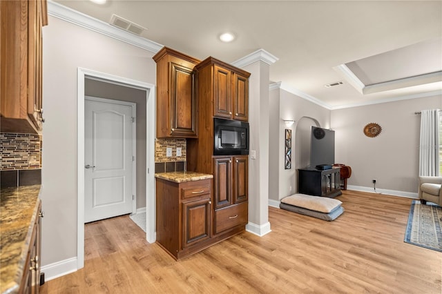 kitchen featuring visible vents, backsplash, open floor plan, black microwave, and crown molding