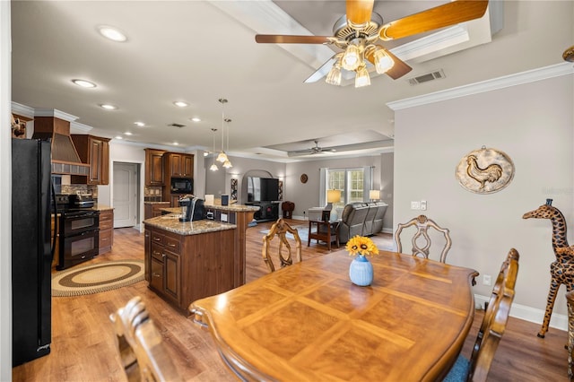 dining room featuring visible vents, ornamental molding, arched walkways, light wood-style floors, and baseboards