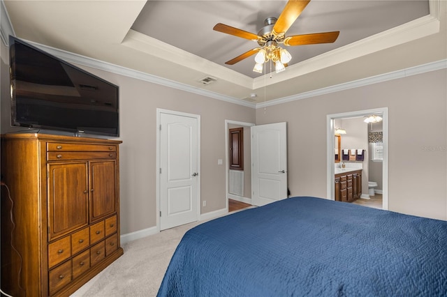 bedroom featuring baseboards, visible vents, ensuite bath, a tray ceiling, and light carpet