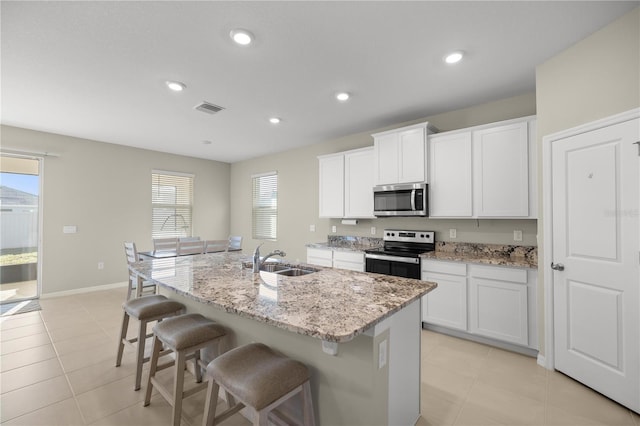 kitchen featuring visible vents, a breakfast bar area, light tile patterned floors, stainless steel appliances, and a sink