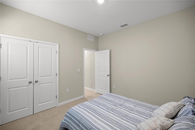 bedroom with light carpet, visible vents, a closet, and baseboards