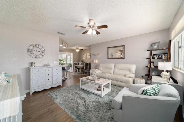 living room with visible vents, baseboards, wood finished floors, a textured ceiling, and a ceiling fan