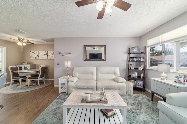 living area with wood finished floors, visible vents, and baseboards