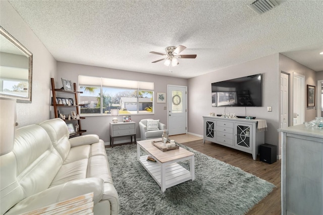 living area with visible vents, baseboards, ceiling fan, and wood finished floors