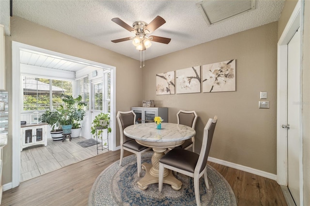 dining area with visible vents, baseboards, a textured ceiling, and wood finished floors