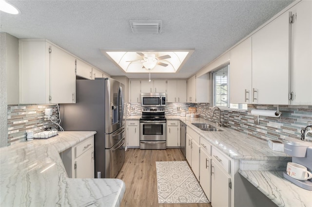 kitchen featuring visible vents, a skylight, light wood-style floors, stainless steel appliances, and a sink