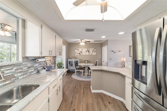 kitchen featuring a ceiling fan, visible vents, stainless steel fridge with ice dispenser, a sink, and backsplash