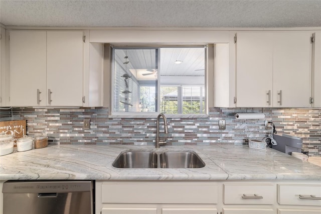 kitchen featuring decorative backsplash, dishwasher, a textured ceiling, and a sink