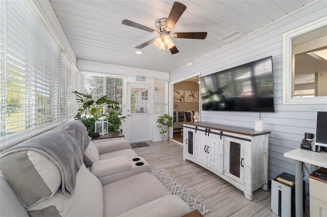 living room with visible vents, ceiling fan, wooden ceiling, and wood walls