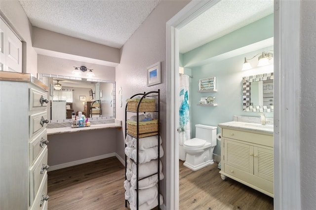 bathroom with toilet, wood finished floors, vanity, and a textured ceiling