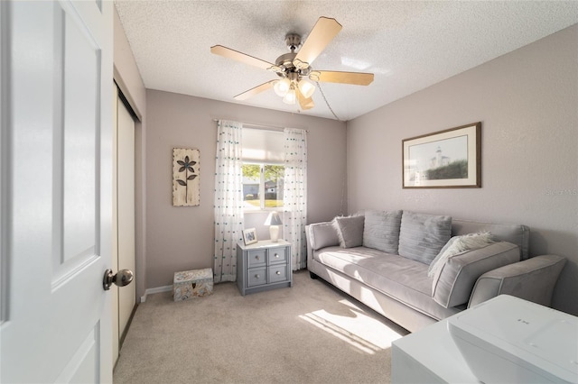 living area featuring light carpet, a textured ceiling, and a ceiling fan