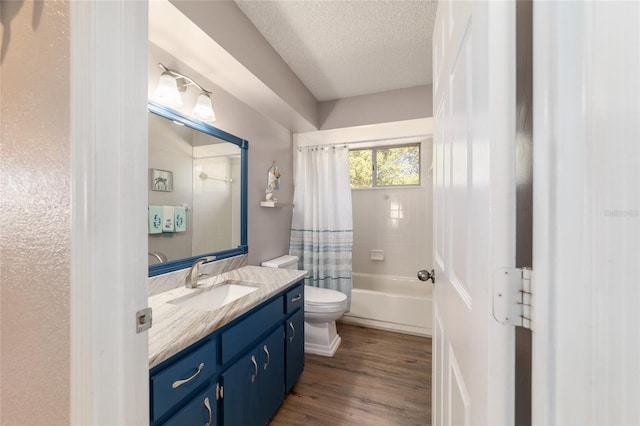 bathroom featuring vanity, wood finished floors, shower / bath combo with shower curtain, a textured ceiling, and toilet