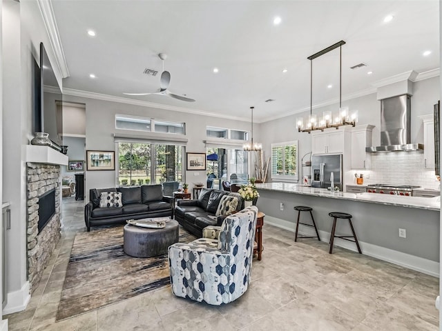 living area with a stone fireplace, visible vents, a healthy amount of sunlight, and crown molding