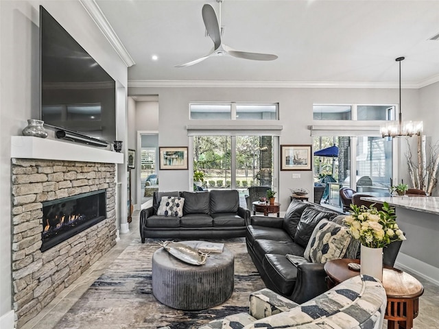 living area featuring plenty of natural light, ornamental molding, a fireplace, and ceiling fan with notable chandelier