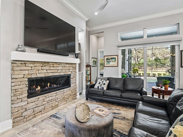 living room with a stone fireplace, crown molding, and baseboards