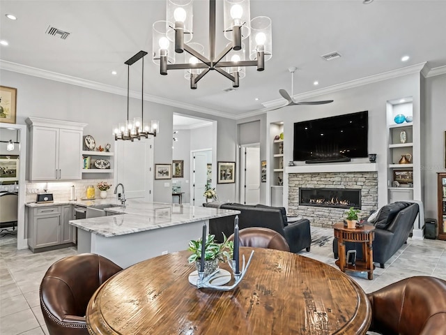 dining room with built in shelves, a fireplace, visible vents, and light tile patterned floors