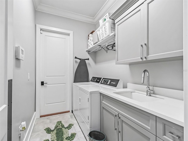 laundry room with baseboards, cabinet space, a sink, crown molding, and washing machine and dryer