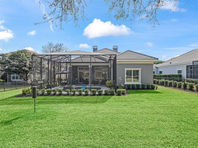 rear view of house with glass enclosure, stucco siding, a chimney, a yard, and a fenced backyard