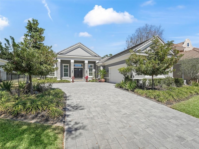 view of front of home with decorative driveway, a garage, and stucco siding