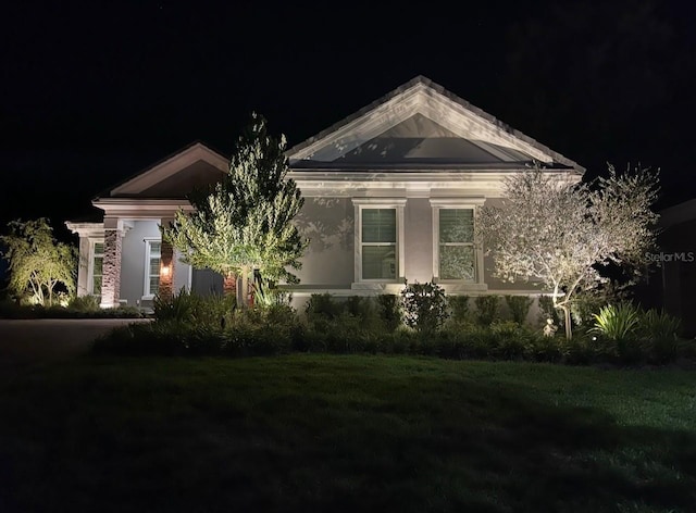 property exterior at twilight featuring a lawn and stucco siding